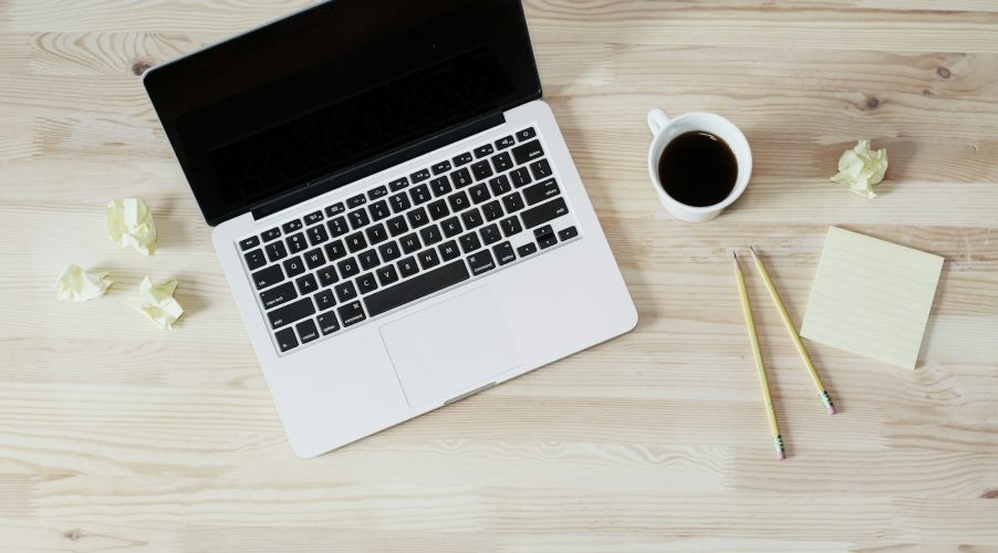 turned off MacBook Pro beside white ceramic mug filled with coffee